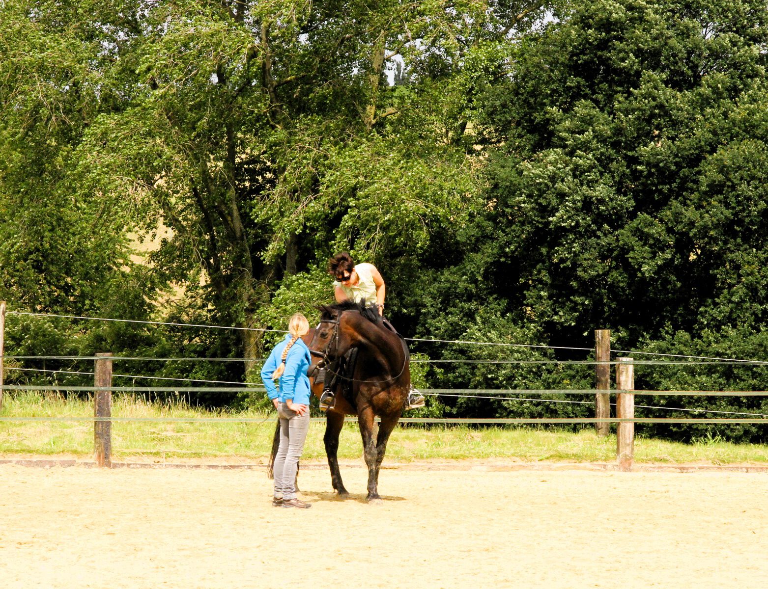 Ein Pferd mit Reiterin, daneben die Reitlehrerin.